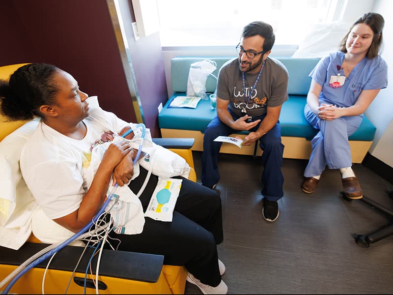 Dr. Maher Ajour and Dr.Brooke McKnight talk with a parent in the NICU about the importance of reading to their child.